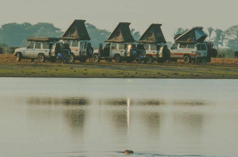Cinco Land Cruiser de Karakoles alineados junto a una laguna del Casanare, con las carpas de techo abiertas
